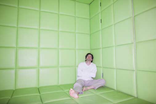 depressed man sitting alone in a padded room